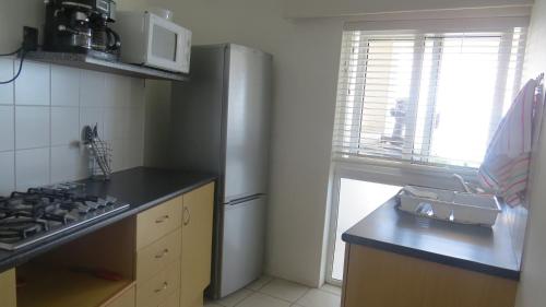 a small kitchen with a refrigerator and a sink at At the Beach in Jeffreys Bay
