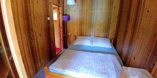 małą sypialnię z łóżkiem w drewnianym domku w obiekcie Domek Schodno w mieście Schodno