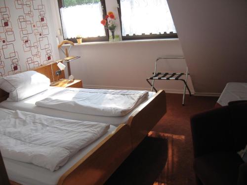 a bedroom with a bed with white sheets and a window at Pension Haus Ursula in Koblenz