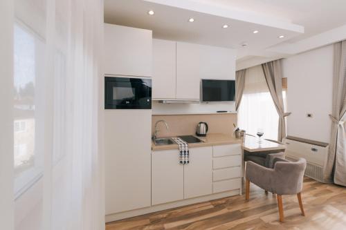 a kitchen with white cabinets and a desk and a chair at Villa Royal Apartments in Tivat