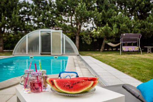 a table with a plate of watermelon on it next to a pool at Vila Les Kralovstvi in Nemojov