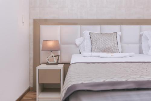 a bedroom with a white bed and a lamp at Villa Royal Apartments in Tivat