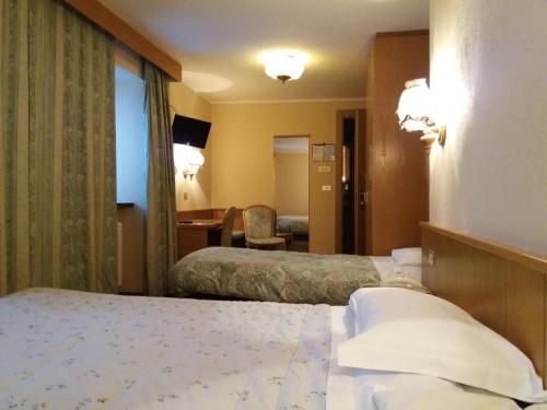 a hotel room with two beds and a desk at Hotel Ottoz Meublé in Courmayeur