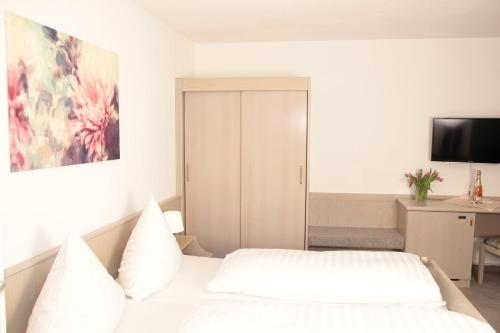 a bedroom with a bed and a desk with a television at Schönblick Hotel Garni Ferienwohnungen in Lindenberg im Allgäu