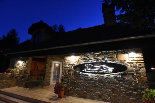 a stone building with a sign on it at night at Cheetah Holiday Club in Vizovice