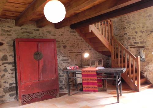 a room with a red door and a table and stairs at Au Son du Jardin Poitevin in Saint-Laurs
