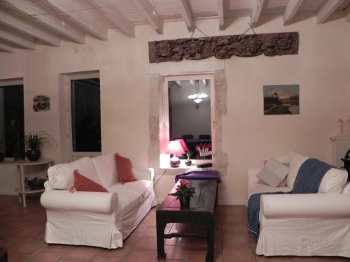 a living room with two white couches and a table at Au Son du Jardin Poitevin in Saint-Laurs