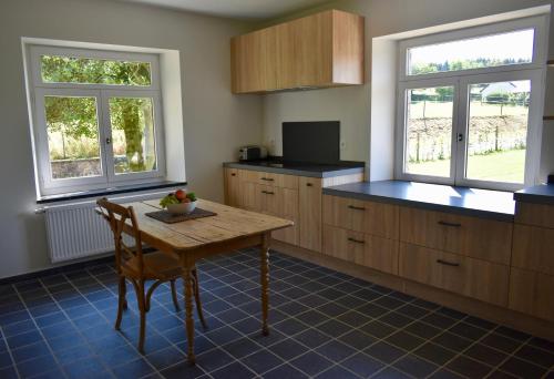 une cuisine avec une table en bois et deux fenêtres dans l'établissement Cottage in Ardennes - La Maison aux Moineaux - Fays-Famenne, à Sohier