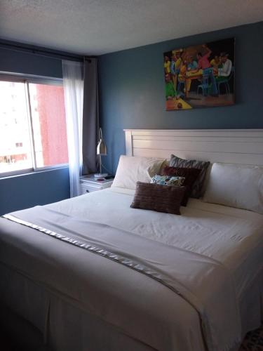 a large white bed in a blue room with a window at McFarlane's Place in Ocho Rios