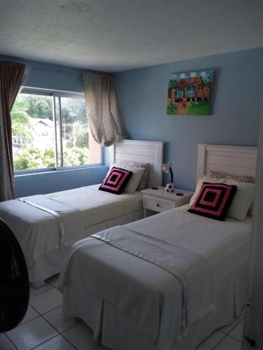 a bedroom with two beds and a window at McFarlane's Place in Ocho Rios