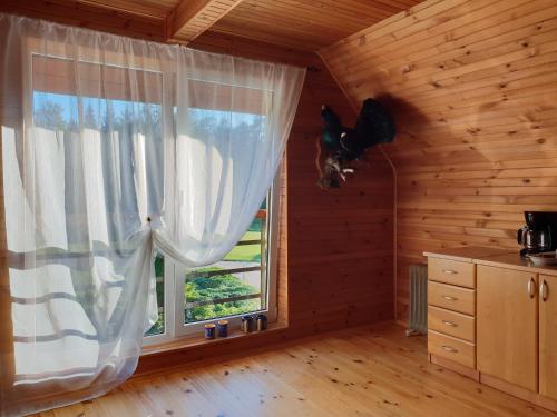 un perro saltando por una ventana en una cabaña de madera en Roguļi, en Cērkste