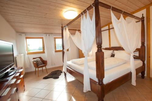 a bedroom with a four poster bed with mosquito netting at Residenz Cheval am Pfaffenberg Friedrichshafen Messe in Oberteuringen