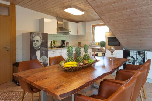 a kitchen with a wooden table with a bowl of fruit on it at Residenz Cheval am Pfaffenberg Friedrichshafen Messe in Oberteuringen
