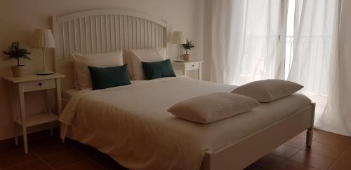 a bedroom with a large white bed with green pillows at Monte Clérigo - Aljezur - Apartamento T2 in Aljezur