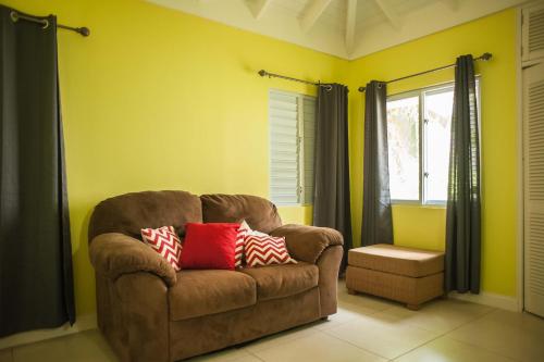 a living room with a brown couch and a window at Jamaica Shades @ Cool Shades in Priory