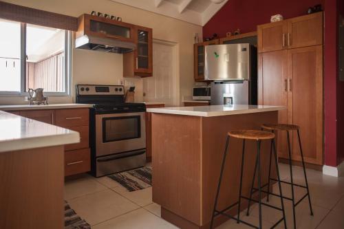 a kitchen with wooden cabinets and an island with bar stools at Jamaica Shades @ Cool Shades in Priory