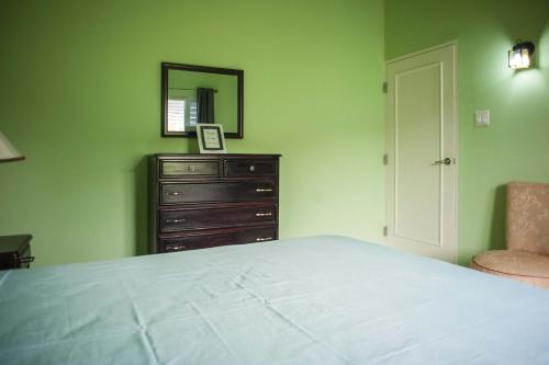 a bedroom with a bed and a dresser and a mirror at Jamaica Shades @ Cool Shades in Priory