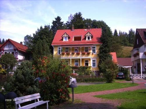 a large house with a red roof and a bench at Erika's Haus in der Sonne in Bad Grund