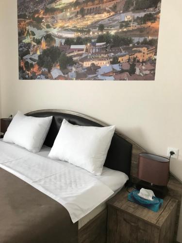 a bed with white pillows and a painting on the wall at Sweet Rooms Inn in Tbilisi City