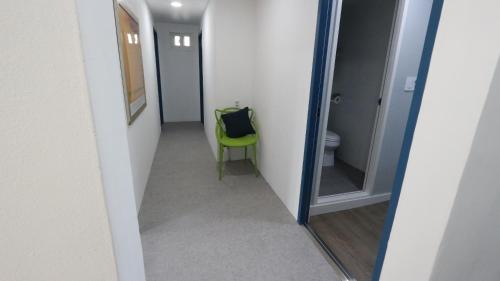 a hallway with a green chair and a mirror at HAH Guesthouse in Seoul
