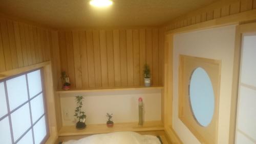a bedroom with wooden walls and a window and a bed at PittINN in Goshogawara