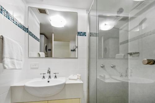 y baño blanco con lavabo y ducha. en Naousa II, en Noosa Heads