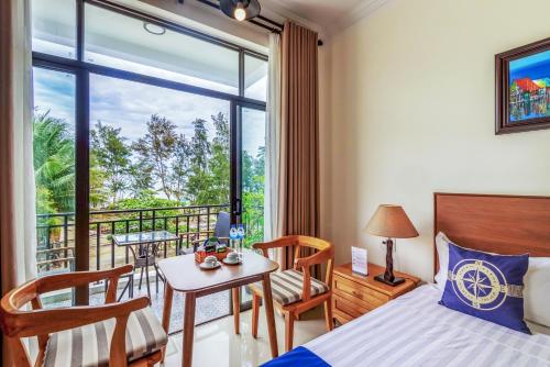 a bedroom with a bed and a table and a balcony at Santa Sea Villa in Hoi An
