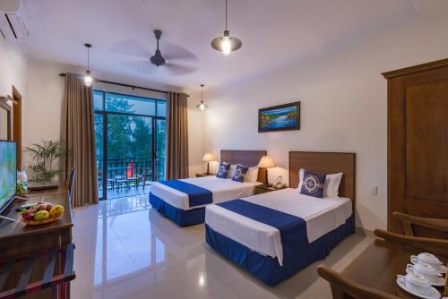 a hotel room with two beds and a balcony at Santa Sea Villa in Hoi An
