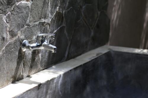 a bathroom sink with a faucet on a stone wall at Baha Baha Villas West Sumbawa Yoyos Wellness Center, Gym, Yoga, Skate Park, Bar & Cafe in Sekongkang