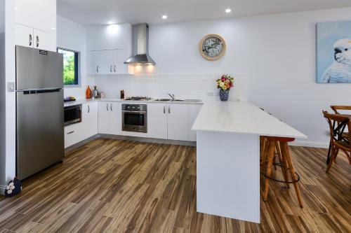 a kitchen with white cabinets and a stainless steel refrigerator at Blue Water Views on Hamilton Island by HIHA in Hamilton Island