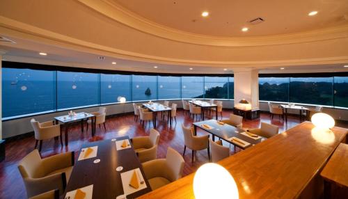a restaurant with tables and chairs and large windows at Onahama Ocean Hotel & Golf Club in Iwaki