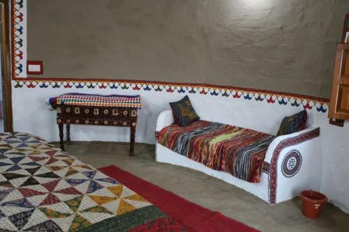 a room with a bed and a chair and a table at Banni Village Resort - Rann Of Kutch in Bherandiāla