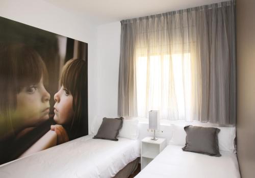 a room with two beds and a painting of a girl at MH Apartments Suites in Barcelona