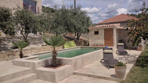 a swimming pool in a yard with two chairs and a house at Le Mas de la Tortue (Plain Pied) in Caromb