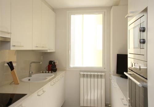 a white kitchen with a sink and a window at MH Apartments Suites in Barcelona
