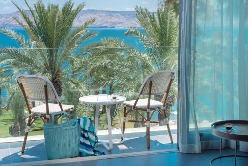 a balcony with two chairs and a table and a view of the ocean at U Boutique Kinneret by the Sea of Galilee in Tiberias