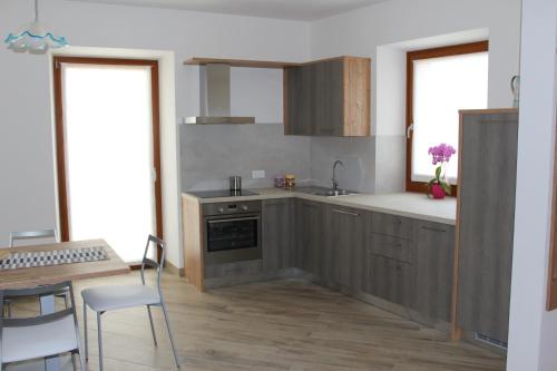 a kitchen with wooden cabinets and a table and chairs at Appartamento Morettina con terrazzo in Levico Terme