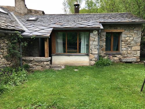 an old stone house with a grass yard at Cal Xandera in Angoustrine