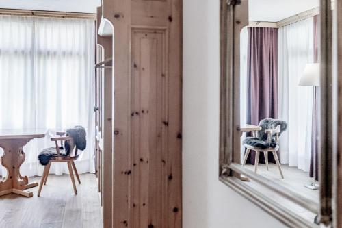 a mirror in a room with a chair and a table at Boutique Hotel Cervus in St. Moritz