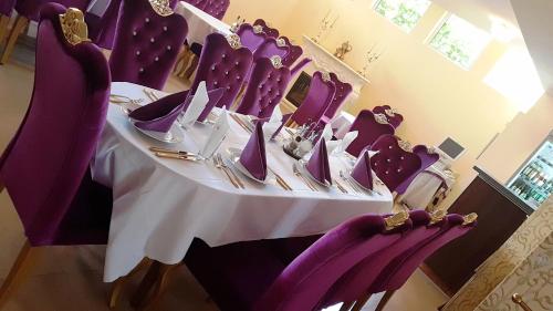 a table with purple chairs and a white table cloth at Hotel Elit Palace and SPA in Balchik