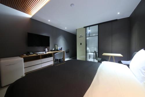 a hotel room with a bed and a desk and a tv at Hotel K in Jeonju