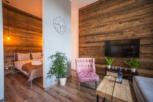 a bedroom with a wooden wall with a bed and a tv at Way2Stay Apartment with parking in Toruń