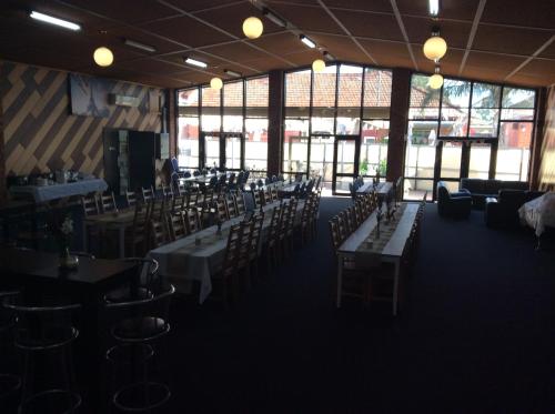 a dining room with tables and chairs and windows at Kerang Motel in Kerang