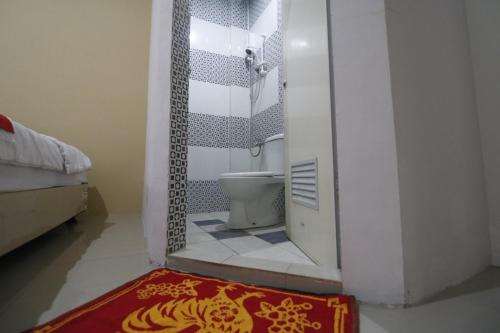 a bathroom with a toilet and a mirror at RedDoorz @ Jalan Krakatau Medan in Medan