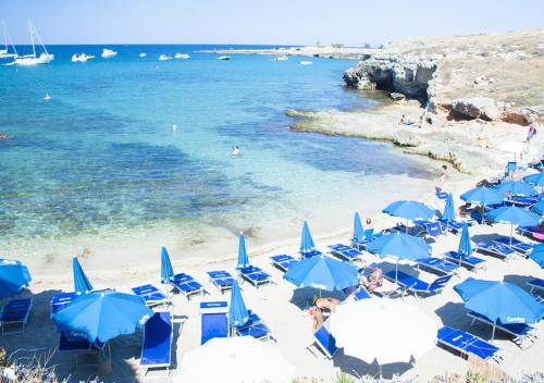 a beach with blue chairs and umbrellas and the ocean at Corvino Resort in Monopoli