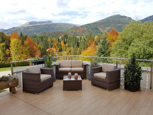 a patio with chairs and tables on a deck with mountains at Landhaus Harmonie in Riezlern