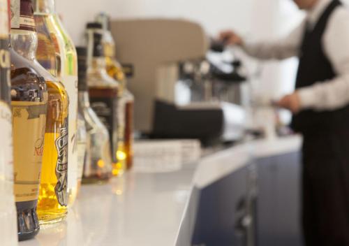 a person standing at a counter with bottles of alcohol at Corvino Resort in Monopoli