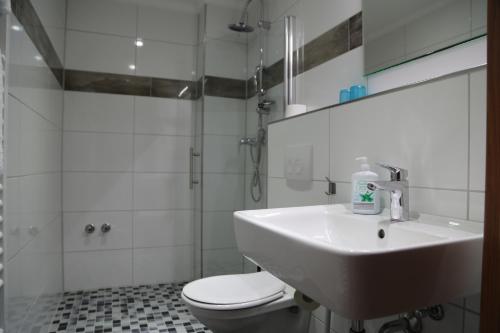a white bathroom with a sink and a toilet at Hotel Mykonos in Eschweiler