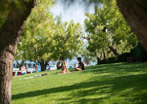 a group of people sitting on the grass in a park at Corvino Resort in Monopoli