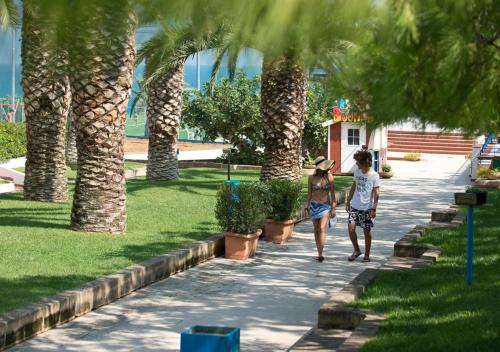two people walking down a sidewalk near palm trees at Corvino Resort in Monopoli